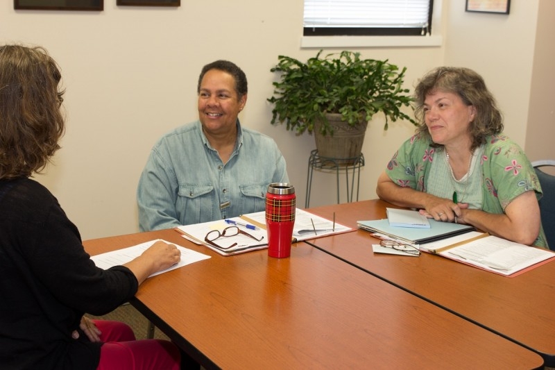 Image of CVCOA Development and Communications Assistant work with others at a table.